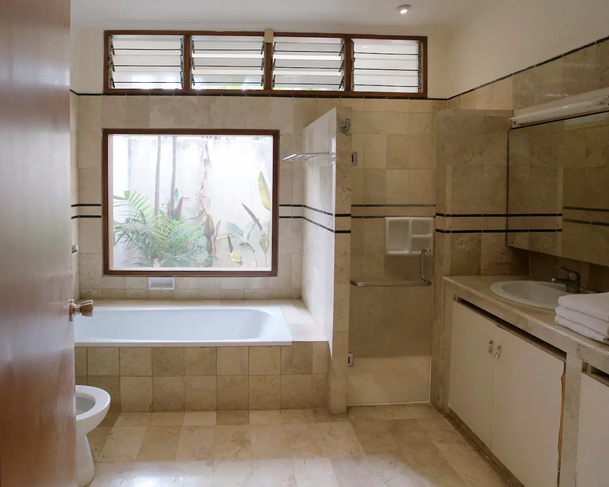 Luxury en-suite bathroom with deep soaking bathtub overlooking private greenery